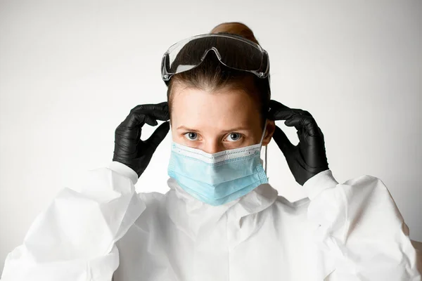 Молодая женщина регулирует медицинскую маску руками — стоковое фото