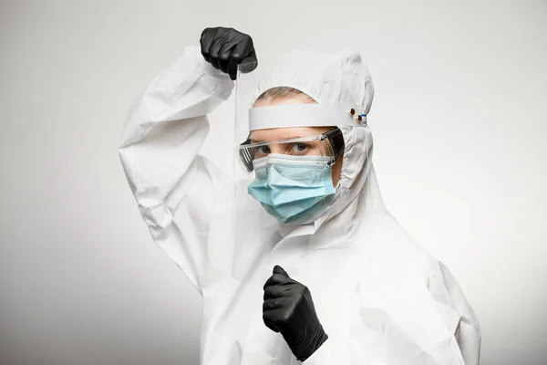 Человек в медицинском защитном костюме стоит в боевой позе на сером фоне — стоковое фото