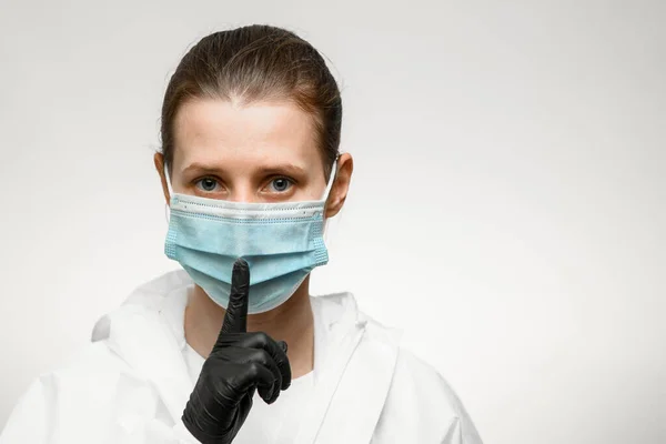 Portrait of woman in medical mask which shows hand silence sign. — Stok Foto