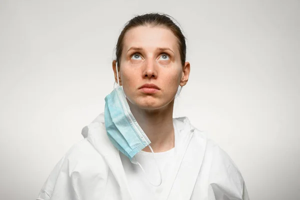 Perawat wanita muda berdiri dengan masker medis yang dihapus dan melihat ke atas — Stok Foto
