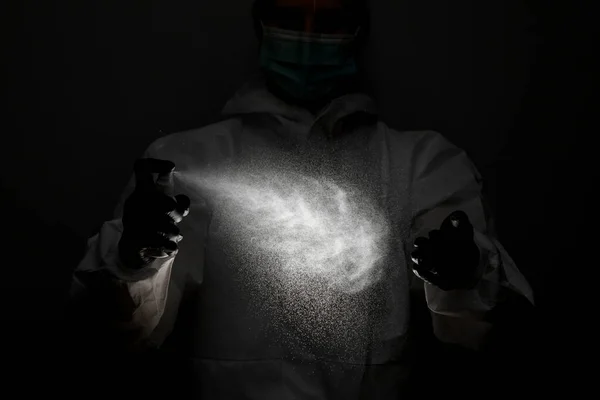 Άτομο σε ιατρικά προστατευτικά ρούχα ψεκάζει απολυμαντικό στα χέρια — Φωτογραφία Αρχείου