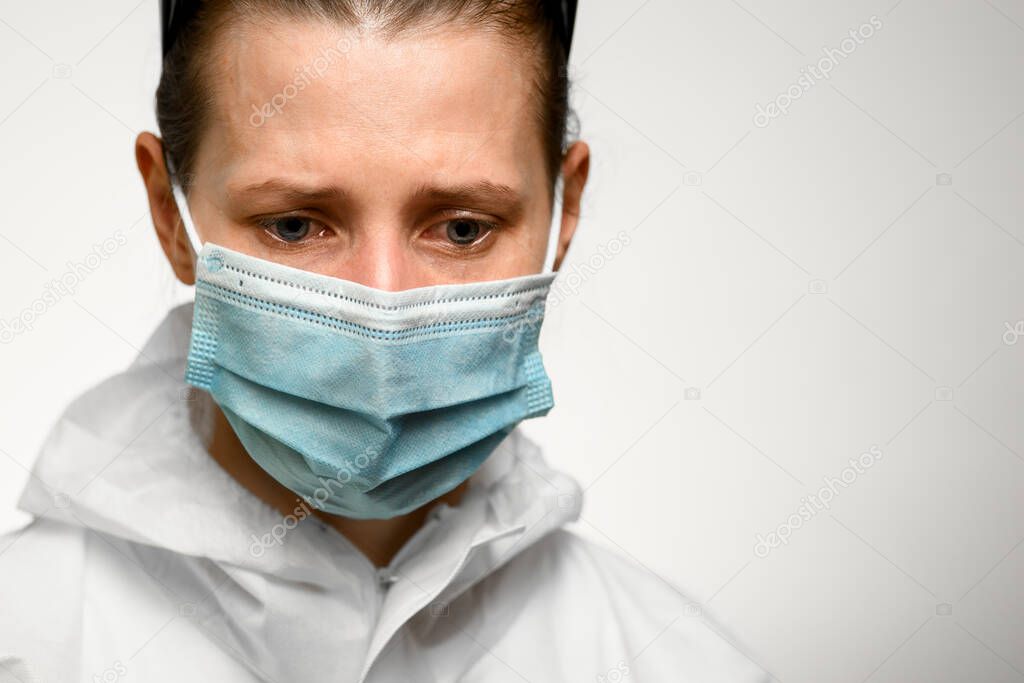 Close-up girl in medical mask with sad expression look down