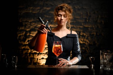 Kadın barmen elinde parlak içecekle portakal suyu tutuyor.