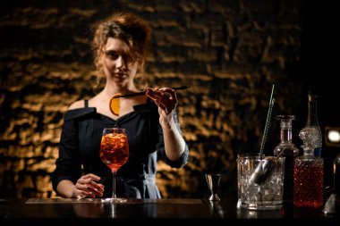 Güzel genç barmen kız bardağı limonla süslüyor.