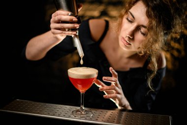 Kadın barmen bardağa köpük koyar ve ona bakar.