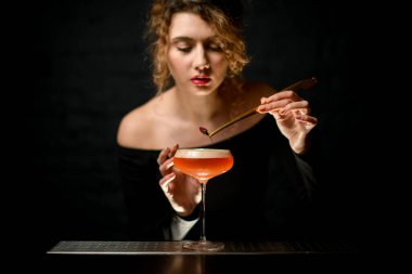 Çekici bayan barmen bardağı köpüklü kokteyl ile güzelce süslüyor..