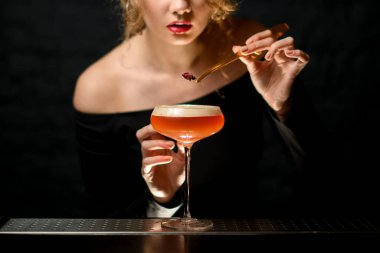 Yakın plan. Kadın barmen, bardağı köpüklü kokteyl ile güzelce süslüyor..