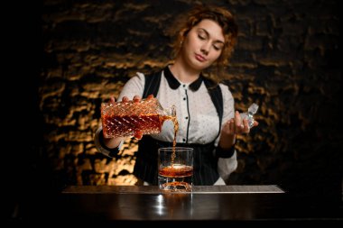 Kadın barmen alkollü içeceği bardaktan bardağa doldurur..