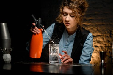 Kadın barmen elinde portakal suyu tutuyor ve suyu kesin olarak döküyor.