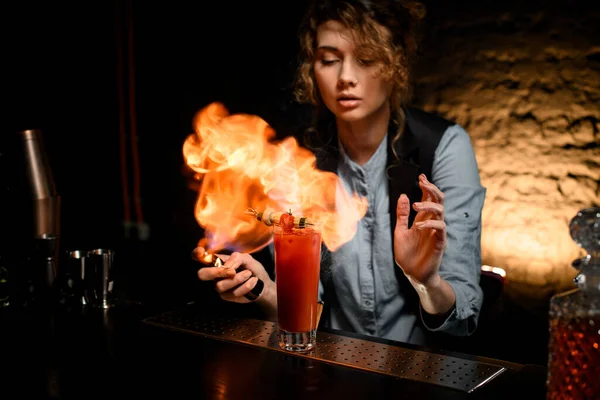 Camarera mujer prendió fuego a fuego sobre vidrio con cóctel . — Foto de Stock