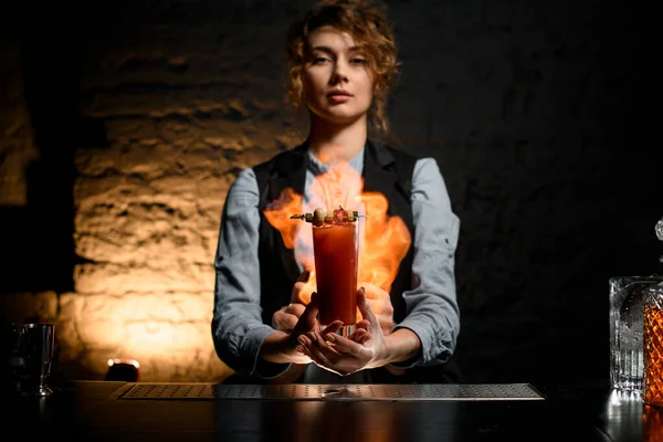 Jovem barman mantém copo de coquetel Bloody Mary e coloca-lo em chamas . — Fotografia de Stock