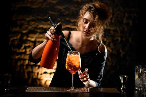 beautiful woman bartender pour liquid from orange siphon to glass with bright drink