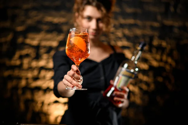 Atractiva joven en el bar sostiene copa de cóctel en la mano extendida — Foto de Stock