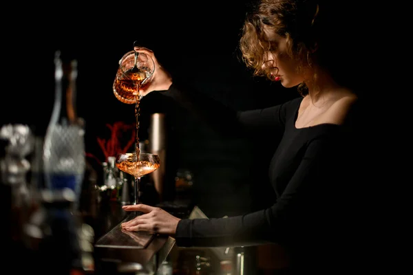 Beauty lady at bar masterfully pours drink into glass — Stock Photo, Image