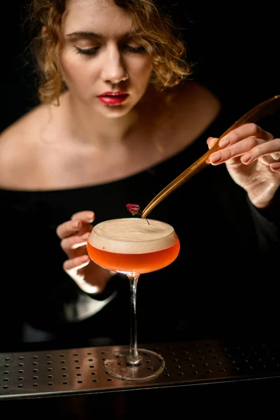 Mooie vrouwelijke barman netjes versiert glas met schuimige cocktail. — Stockfoto