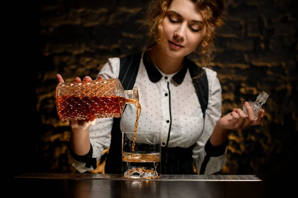 Bartender mulher precisa derrama bebida alcoólica de decantador em vidro . — Fotografia de Stock