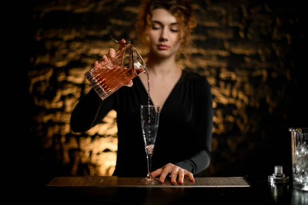 Beauty woman at bar accurate pours drink into glass