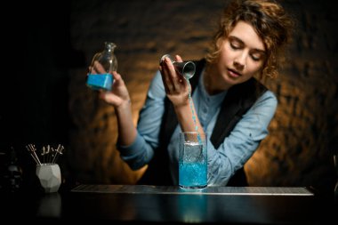 Profesyonel kadın barmen Jigger 'dan soğuk su bardağına su doldurur.