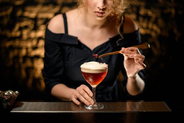 Kadın barmen bardağı köpüklü kokteyl ile güzelce süslüyor..