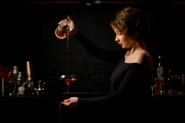 Bardaki seksi kadın ustaca bardaklara içki dolduruyor.