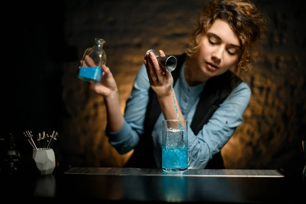 Επαγγελματική γυναίκα μπάρμαν χύνει ποτό από jigger σε ποτήρι κρύο νερό — Φωτογραφία Αρχείου