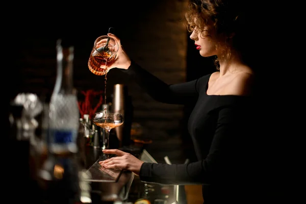 Красавица в баре мастерски наливает напиток в стекло — стоковое фото