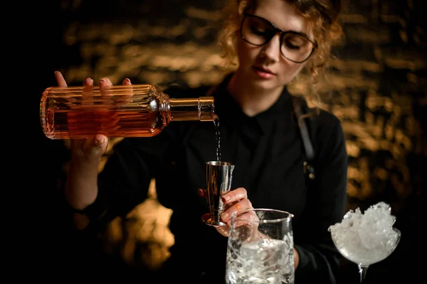 Garçom fêmea derrama licor em jigger de aço . — Fotografia de Stock