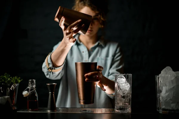 Jovem no bar derrama bebida de um copo de metal para outro — Fotografia de Stock