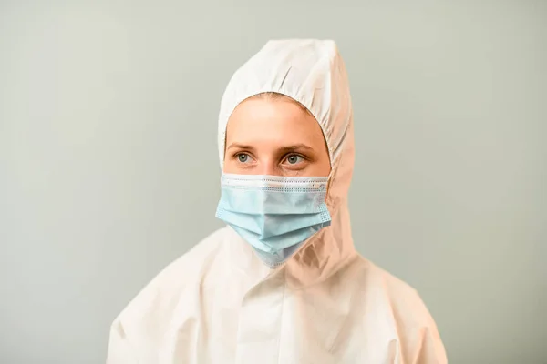 Портрет молодой медик в белом защитном костюме с капюшоном на сером фоне . — стоковое фото