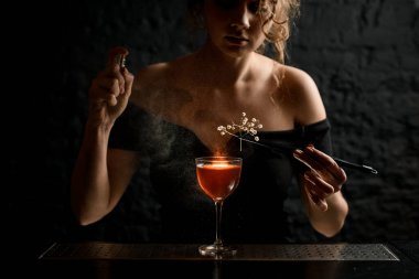 Genç bayan barmen beyaz çiçekli cımbızla cam süsler..