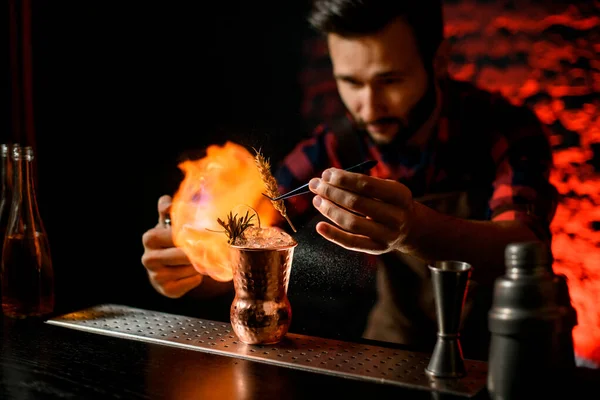 Hombre en el bar decora vidrio con cóctel y le prende fuego — Foto de Stock