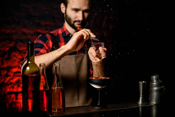 Barmen büyük bir buz parçası tutuyor ve kırıyor. — Stok fotoğraf