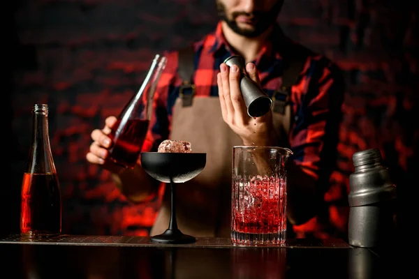 Barman suavemente derrama bebida de jigger em vidro de mistura . — Fotografia de Stock