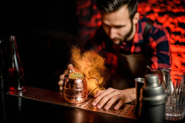 Mannelijke barman hagelslag op metalen beker met cocktail op bar teller. — Stockfoto