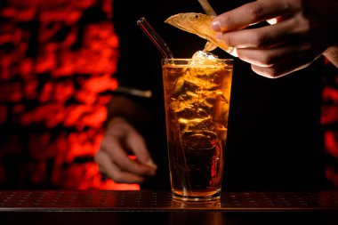 Yakın plan. Barmenler bardağı içkiyle süsler.