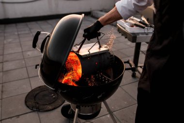 Adam dikkatlice barbekü ızgarasına kömür döker..