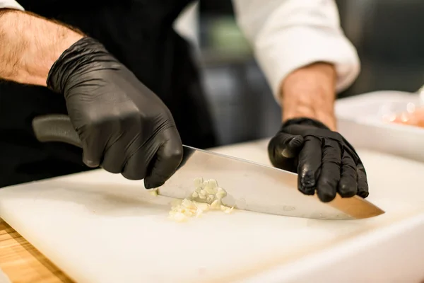 Een close-up. Mannelijke kok hak de knoflook met mes — Stockfoto