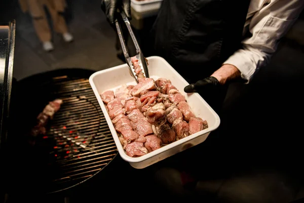 トンズのある男性シェフが生肉をバーベキューグリルで広げ — ストック写真