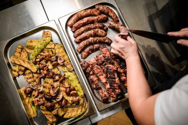 Izgara et ve sebzeli iki metal tepsi.