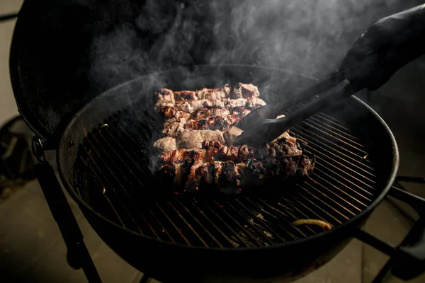 プロの男性が正確にトンを使用してターンを調理グリル上の肉のクローズアップ. — ストック写真