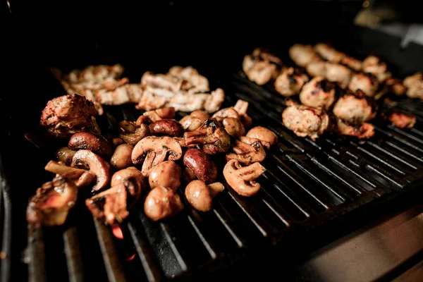 Close-up da grelha com cogumelos fritos e pedaços de carne . — Fotografia de Stock