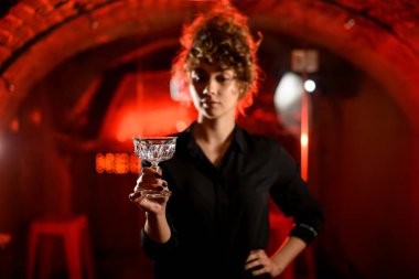 Genç bir kadın önünde boş bir bardak tutuyor ve ona bakıyor..