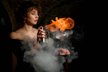 Güzel bir kadın bardağa su sıçratır, serper ve üzerine ateş yakar..