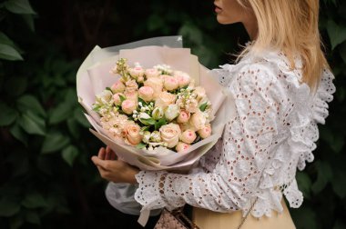 Genç ve çekici bir kadın elinde bir buket gül tutuyor..