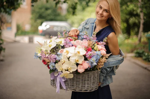 Primer plano de la mujer que sostiene la cesta enorme con diferentes flores . — Foto de Stock