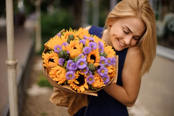 젊은 금발 여성 이 밝은 여름 꽃다발을 들고 있습니다 — 스톡 사진