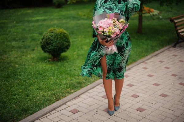 Kobieta z bukietem kwiatów spacery w parku. — Zdjęcie stockowe