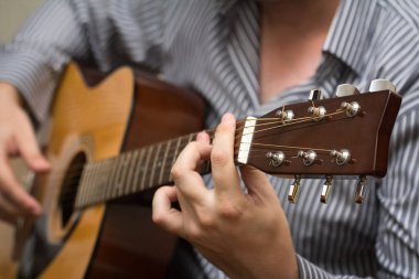 Akustik gitar çalan kimliği belirsiz bir adam. Seçici odak.