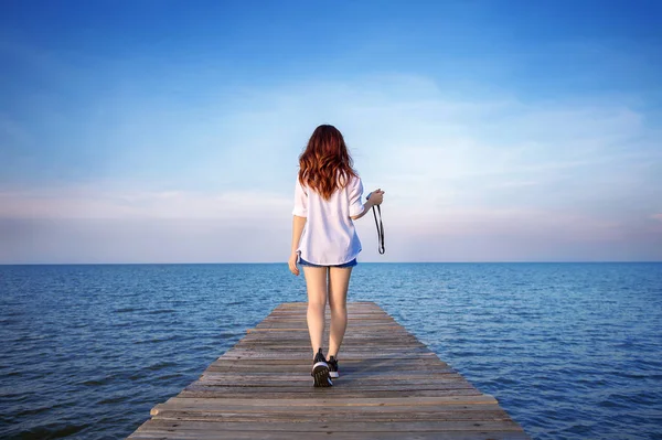 Mujer caminando sobre puente de madera extendido en el mar . —  Fotos de Stock