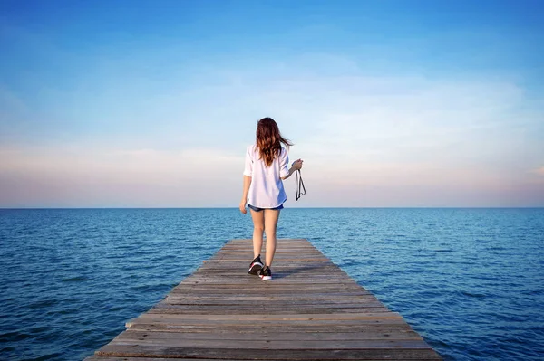 Frau läuft auf Holzbrücke ins Meer. — Stockfoto